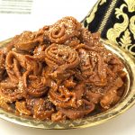 A mound of Moroccan chebakia cookies are mounded on a decorative metal tray.