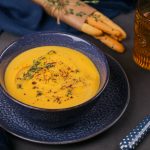 A bowl of pureed vegetable soup garnished with herbs